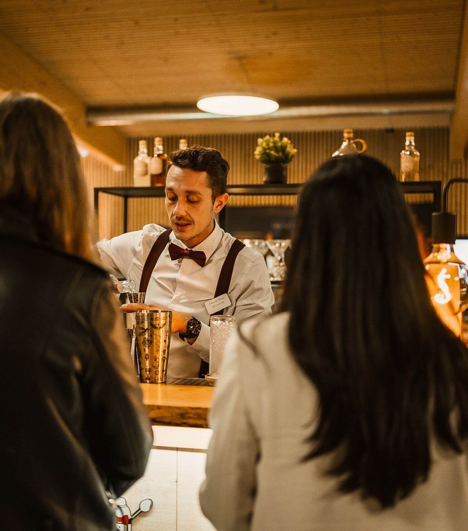 Mr Cocktail avec deux clientes devant le bar lors d’un événement d'entreprise en Suisse